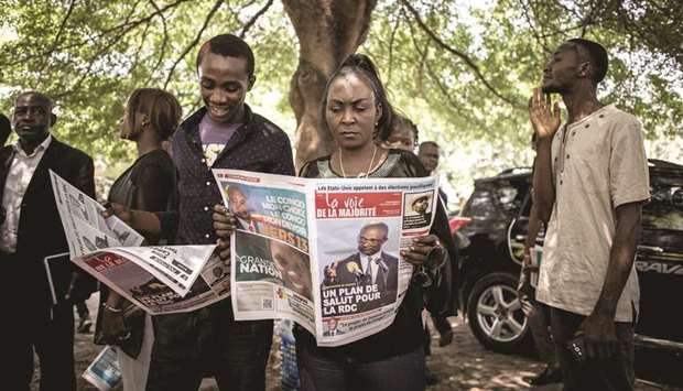 Supporters of the official DR Congo presidential candidate, Emmanuel Ramazani Shadary, read a newspaper outside the Cathedral Notre-Dame Du Congo in Kinshasa.