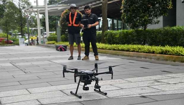 Staff members of Singapore technology firm H3 Dynamics preparing to fly a drone to inspect a building facade in Singapore.