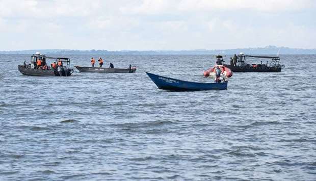 Local fishermen and Ugandan Navy personnel search passengers of capsized  boat on lake Victoria at Mutima village