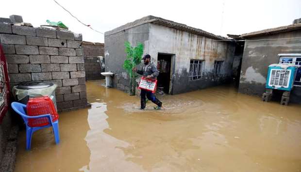 A man cleans his house after heavy rainfall in al-Aziziyah, Iraq