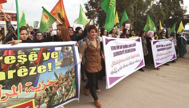 Syrian Kurdish women raise banners reading in Kurdish and Arabic u201cwomanu2019s freedom is by  revolution, protect your revolutionu201d (left) and u201cby womenu2019s free will we will destroy the occupationu201d (centre and right), as they demonstrate in the city of Qamishli yesterday, as they mark the International Day for the Elimination of Violence against Women.