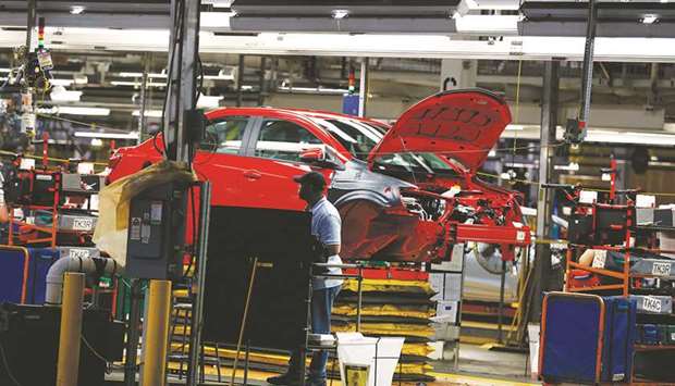 An employee stands next to a Chevrolet Sonic vehicle on the production line at the General Motors Assembly Plant in Orion Township, Michigan. GM plans to announce a broader restructuring of its efforts as it shifts more of its focus toward electrified and autonomous vehicles, a source said.