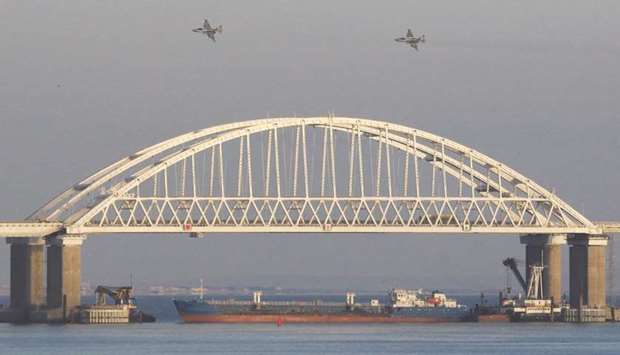 Russian jet fighters fly over a bridge connecting the Russian mainland with the Crimean Peninsula with a cargo ship beneath it after three Ukrainian navy vessels were stopped by Russia from entering the Sea of Azov via the Kerch Strait in the Black Sea.