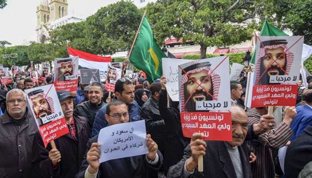 Tunisians shout slogans and hold up signs as they protest against the expected visit of the Saudi Crown Prince to the country, in Habib Bourguiba Avenue in the capital Tunis