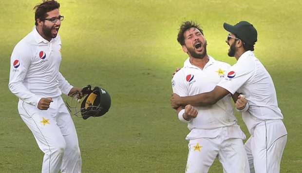 Pakistanu2019s Yasir Shah (centre) celebrates the wicket of New Zealandu2019s Trent Boult (not pictured) with teammates Hasan Ali (right) and Imam-ul-Haq on the fourth day of the second Test in Dubai yesterday. (AFP)