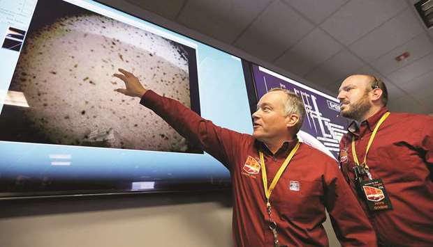 FIRST DAY, FIRST SHOW: Tom Hoffman, left, InSight Project Manager with Jonny Grinblat look at the first image beamed back after the successful landing of the Nasa InSight spacecraft in the Mission Support Area of the Space Flight Operation Facility at JPL in Pasadena.