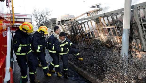 Firefighters work next to burnt vehicles following a blast near a chemical plant in Zhangjiakou