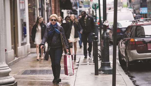 A woman carries a shopping bag while walking in the Center City area of Philadelphia, Pennsylvania. The strong consumer spending reported by the Commerce Department yesterday probably keeps the US central bank on track to raise interest rates next month for the fourth time this year.