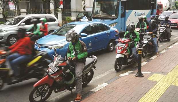 Go-Jek motorcycle taxi drivers check their smartphones at a roadside in Jakarta. Go-Jeku2019s beta app will become available on Android and Apple devices to a limited number of consumers in Singapore as it gets its ride-hailing business running in the country, the company said in a statement yesterday.
