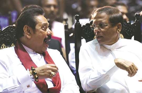 President Maithripala Sirisena, right, speaks with former president and currently appointed prime minister Mahinda Rajapakse at a ceremony granting employment to social service workers, in Colombo yesterday.