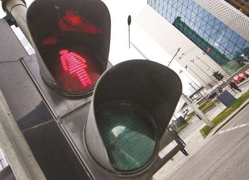 Pedestrian lights in Vilnius showing a female silhouette are seen at a crosswalk.