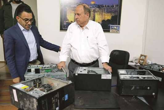 Member of Fatah movementu2019s executive council and minister in charge of the Jerusalem  affairs for the Palestinian Authority Adnan al-Husseini (right) and Governor of Jerusalem for the Palestinian Authority Adnan Gheith pose for a photograph with damaged computers at the Palestinian Ministry of Jerusalem affairsu2019 headquarters in the town of Al-Ram, yesterday.