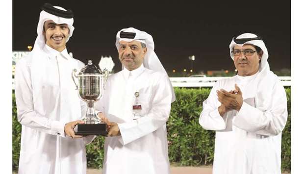Al Shaqab Equestrian Facility Expert Majid Nasser al-Kaabi (centre) presents the owneru2019s trophy to Khalifa bin Sheail al-Kuwari after Scudding won the Qatar Cup at the Qatar Racing and Equestrian Clubu2019s Al Rayyan Park yesterday. PICTURES: Juhaim