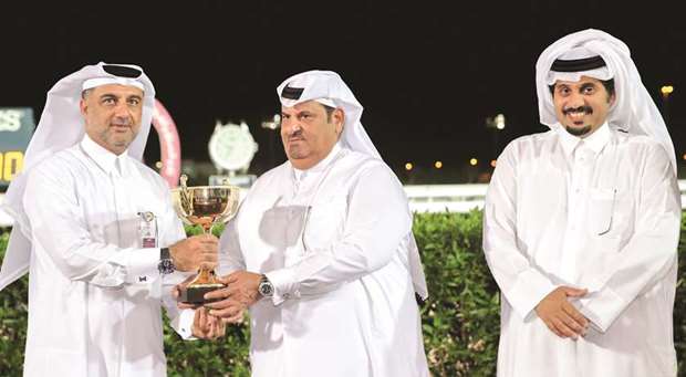 Hassan Ali al-Abdulmalik (left) receives the owneru2019s trophy in the presence of QREC general manager Nasser Sherida al-Kaabi (right) after Almuheet won the Losail Cup yesterday. PICTURES: Juhaim