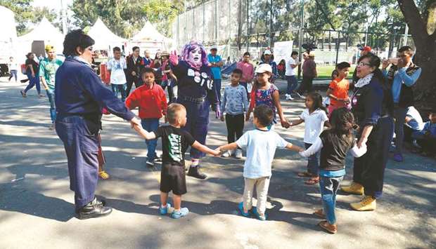 Entertainers play with Central American migrant children taking part in a caravan towards the US, at a shelter set up at the Sports City in Mexico City during a stop in their journey.