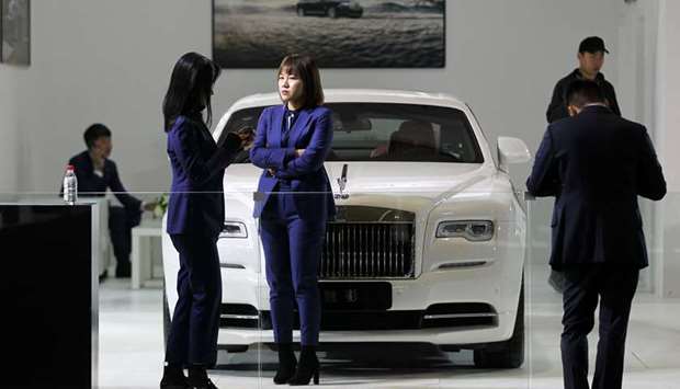 People stand next to a Rolls-Royce Wraith car displayed at an auto show in Kunming, Yunnan province. Chinau2019s automobile sales fell 11.7% in October, bringing the worldu2019s biggest car market closer to an annual contraction not seen since at least 1990.