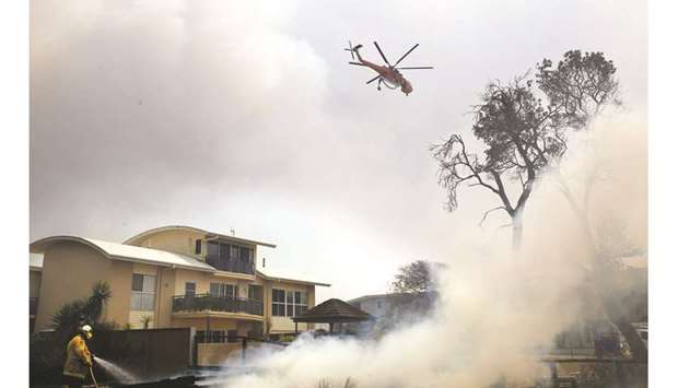A fire bombing helicopter works to contain a bushfire along Old Bar road in Old Bar, New South Wales yesterday.