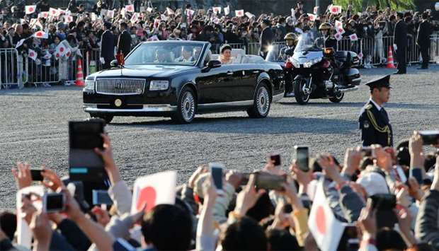 People cheer as the motorcade of Japanu2019s Emperor Naruhito and Empress Masako leaves the Imperial Palace during a royal parade in Tokyo