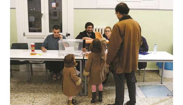 A man with two children take part in the voting process at a Madrid polling station during the general election.