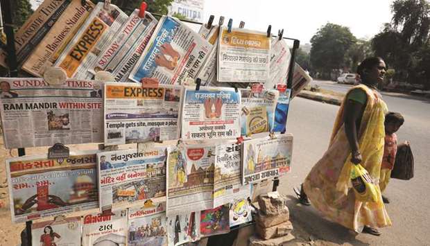 A woman walks past newspapers hanging at a stall with the headlines about Supreme Courtu2019s verdict on Ayodhya, in Ahmedabad, yesterday.