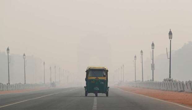 An auto-rickshaw moves past the India Gate on a smoggy morning in New Delhi