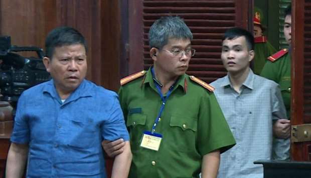 Police escort Chau Van Kham (L) and Tran Van Quyen (R) to their trial at a court in Ho Chi Minh city, Vietnam