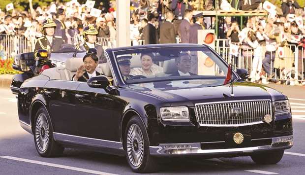 Japanu2019s Emperor Naruhito and Empress Masako wave during a royal parade in Tokyo.