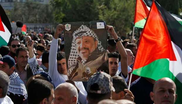 Hundreds of Palestinians gather with national flags in front of the tomb of late Palestinian leader Yasser Arafat (portrait) on the 15th anniversary of his death