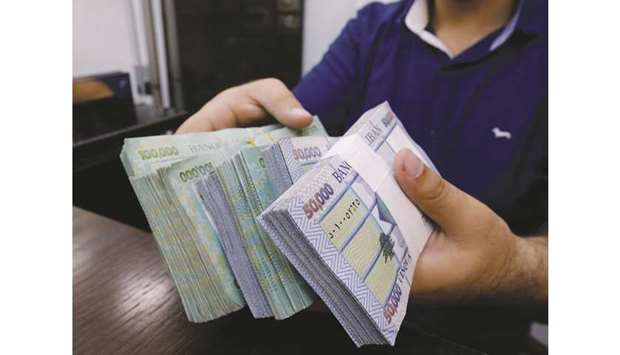 A money exchange vendor displays Lebanese pound banknotes at his shop in Beirut (file). Lebanonu2019s central bank, seeking to shore up battered confidence in the financial system amid the worst  economic crisis in decades, said yesterday bank deposits are secure and it had the ability to preserve the stability of the pegged Lebanese pound.