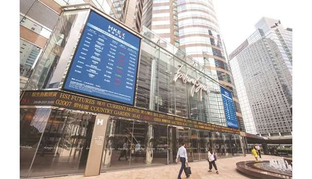 Pedestrians walk past an electronic ticker board and a screen displaying stock figures outside the Exchange Square complex, which houses the stock exchange in Hong Kong (file). The abrupt drop in the cityu2019s stocks yesterday u2014 the worst in Asia u2014 follows a half trillion dollar rally that drove a measure of buying momentum to its highest level in almost nine months and pushed the Hang Seng Index above its 200-day moving average.