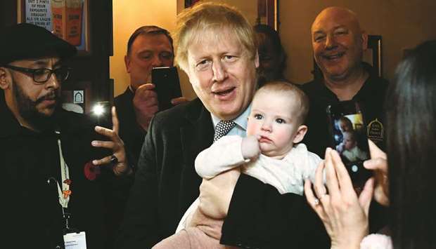 Britainu2019s Prime Minister Boris Johnson holds a baby as he meets supporters at the Lynch Gate Tavern in Wolverhampton, Britain, yesterday.