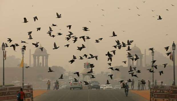 Birds fly as people commute near India's Presidential Palace on a smoggy day in New Delhi, India