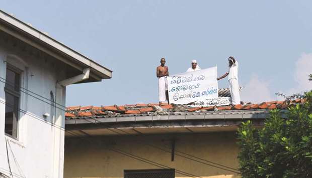 Prisoners display a banner on the roof of a building inside the Welikada prison in Colombo yesterday, to protest the pardon for man who murdered a Swedish teenager in 2005.
