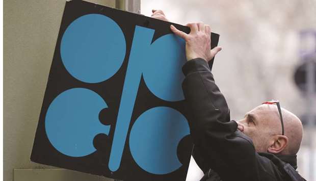 A man fixes a sign with the Opec logo next to its headquarteru2019s entrance before a meeting of Opec oil ministers in Vienna, Austria (file). Crude prices, trading at about $62 a barrel in London, may tumble almost 30% to $45 a barrel if Opec and its allies donu2019t announce deeper production cutbacks, according to Morgan Stanley.