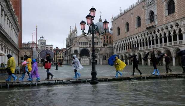 People walk on a catwalk in the flooded St Marku2019s Square in Venice.