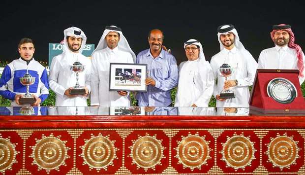 Umm Al Houl Power Company CEO Jamal Ali al-Khalaf (third from left) and QREC deputy chief steward Abdulla al-Kubaisi (third from right) pose with the winners of the Umm Al Houl Cup after Receding Waves won the six-furlong sprint at QREC yesterday. PICTURES: Juhaim