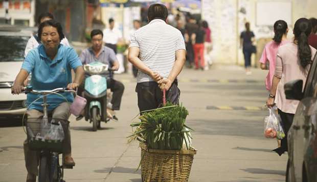 A man pulls a basket of leeks as he walks along a road near an open market in Beijing (file).