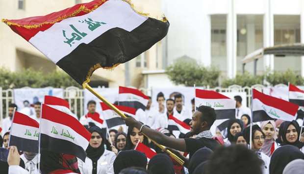 Iraqi medical students wave national flags during an anti-government protest at the campus of the university of Basra yesterday.