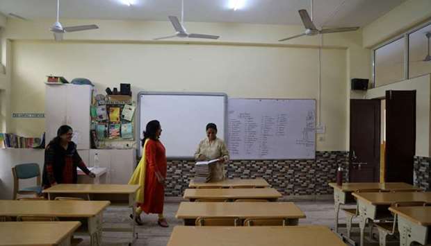 Teachers talk to each other in an empty classroom of a school after it remained closed on account of smog in New Delhi, India