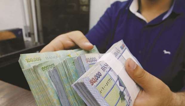 A money exchange vendor displays Lebanese pound banknotes at a shop in Beirut (file). Three top banks in Lebanon were downgraded below the sovereign by S&P Global Ratings, which warned that the countryu2019s economic crisis is draining liquidity from lenders that have stayed shuttered for much of the past month because of anti-government unrest.