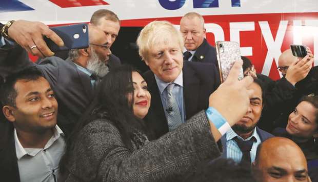 Prime Minister Boris Johnson poses for a picture with a supporter in front of the general election campaign trail bus in Manchester, Britain, yesterday.