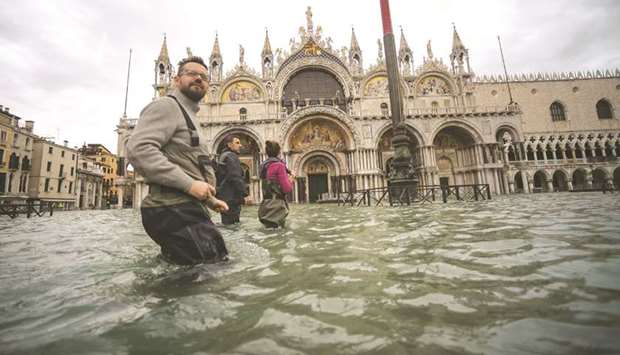 A general view shows people walking yesterday across the flooded St Marku2019s Square, by St Marku2019s Basilica, in Venice, two days after the city suffered its highest tide in 50 years.
