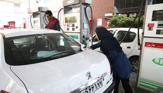 A woman fills up her car's tank at a petrol station, after fuel price increased in Tehran. Reuters