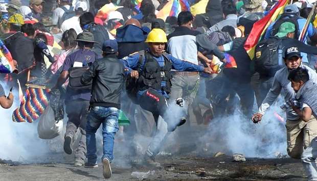 Coca growers, supporters of former President Evo Morales, run away from tear gas as one of them kicks a tears gas canister during clashes with riot police in Sacaba, in the outskirts of Cochabamba, Bolivia. Reuters