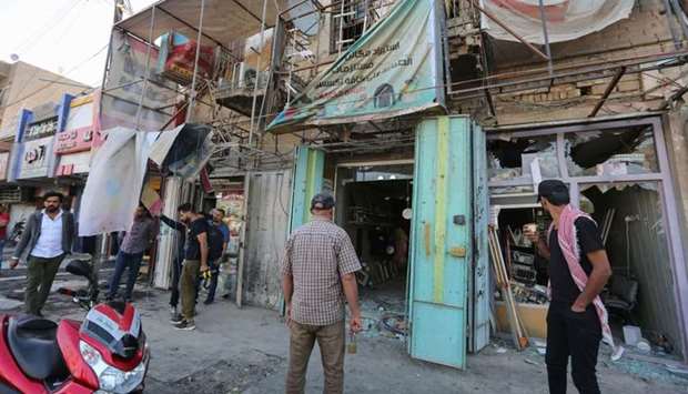Iraqis stand at the site of a bomb explosion near Baghdad's Tahrir Square. AFP