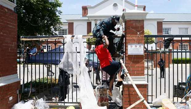 A refugee helps another to attempt to climb over the fence into the United Nations High Commissioner for Refugees (UNHCR) office premises in Pretoria