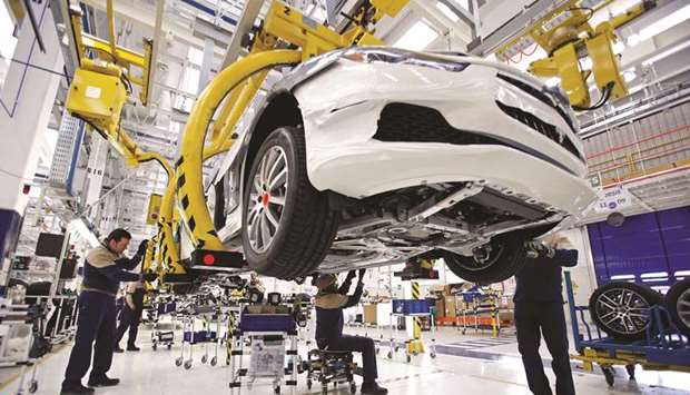 Employees work on a Maserati automobile as it travels along the production line at Fiatu2019s Grugliasco factory in Turin (file). A number of car-components makers are clustered throughout Lombardy and Piedmont, whose capital Turin is birthplace of Agnelli family-founded Fiat.