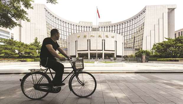 A man rides a bicycle past the Peopleu2019s Bank of China headquarters in Beijing. The economy faces greater difficulties as investment growth slows and industrial production remains sluggish, the bank said in its third-quarter monetary policy report released yesterday.