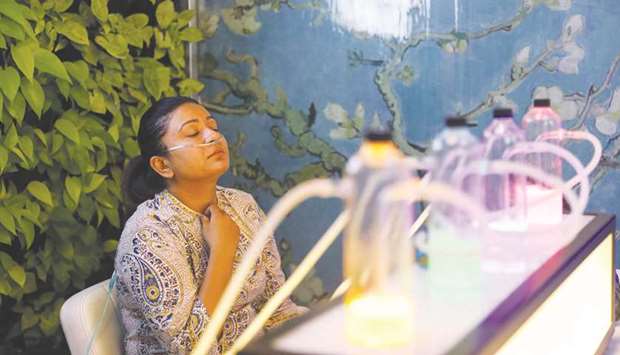 A woman breathes in oxygen mixed with aromatherapy via a nasal cannula, at an oxygen bar in New Delhi.