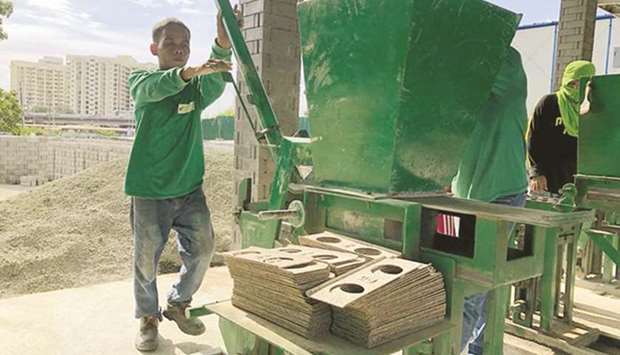 A man operates a brick-pressing machine that mixes shredded sachet laminates with wet cement to produce an ecobrick at a facility run by Green Antz Builders Inc in Taguig City. (Xinhua Photo/ Manila Times)